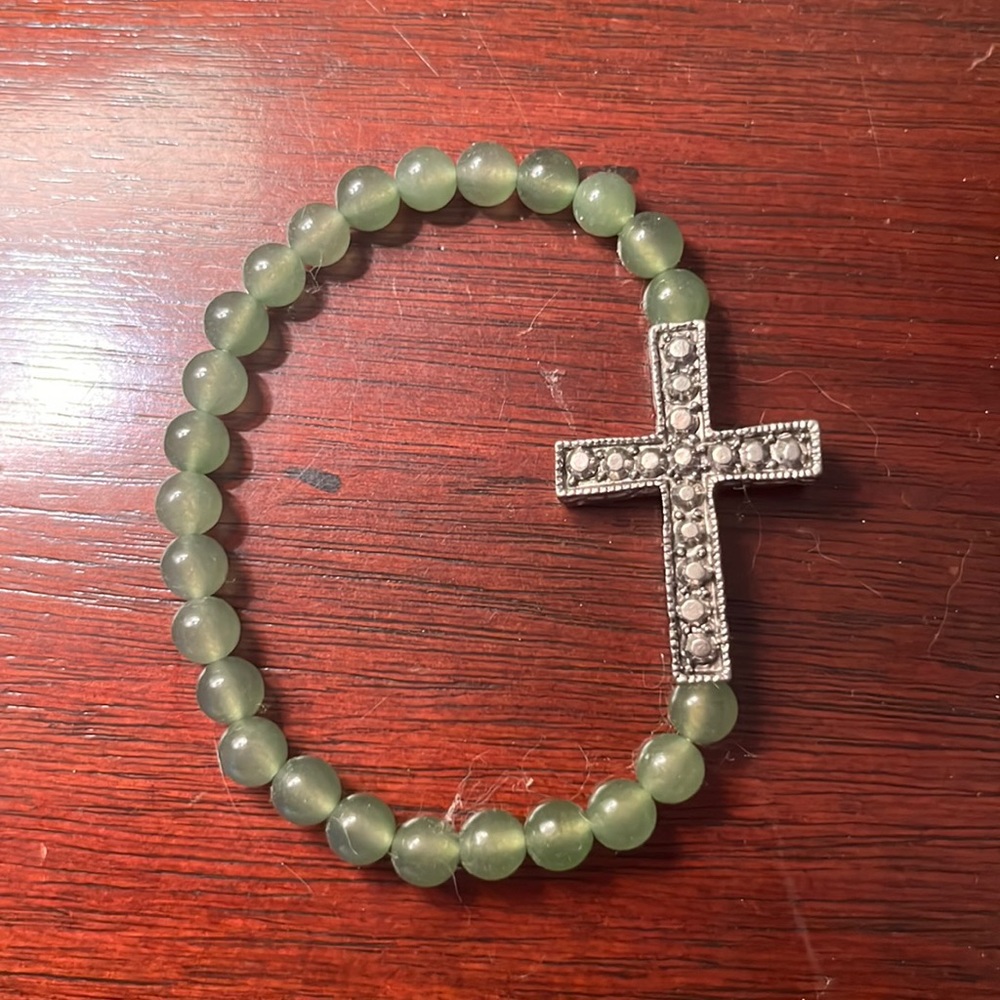 Green bracelet with a cross on it.